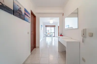 a hallway with white walls and white tile floors at Quarteira Beach - 2 D by HelloVacations in Loulé