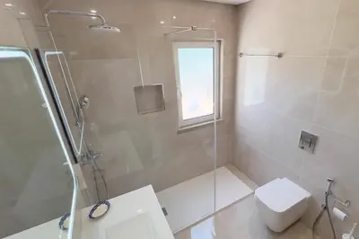 a bathroom with a shower and a toilet and a window at Villa Dantas by amcf in Vilamoura