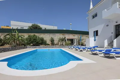 a swimming pool with chairs and a building at Apart Quinta dos Martins - swimming pool - BY BEDZY in Albufeira