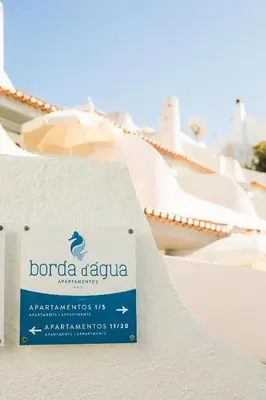 a patio with chairs and an umbrella and the ocean at Apartamentos Borda D´Agua in Albufeira