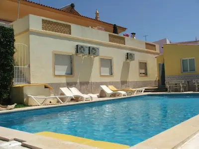 a swimming pool with chairs and a house at Apartamento Studio Anastacio in Albufeira