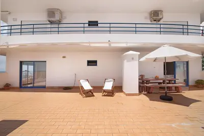 a patio with a table and an umbrella at Pérola do Atlântico By the Sea in Quarteira