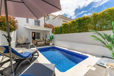 a villa with a swimming pool and an umbrella at Casa Perola - Vale do Garrão in Almancil