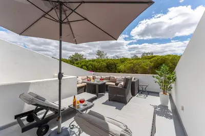 a patio with an umbrella and chairs and a table at Casa Perola - Vale do Garrão in Almancil