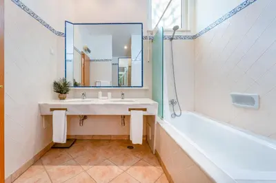 a bathroom with a sink and a tub and a mirror at Casa Perola - Vale do Garrão in Almancil