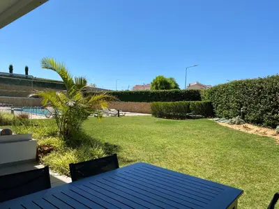 a patio with a blue table and a grass yard at Albufeira Malpique Beach Apartment in Albufeira