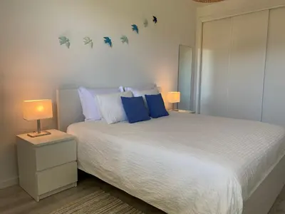 a bedroom with a large bed with blue pillows at Albufeira Malpique Beach Apartment in Albufeira