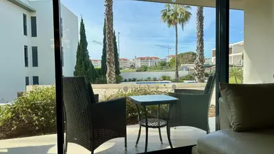 a patio with a table and chairs and palm trees at Cavalo Branco Portugal in Quarteira