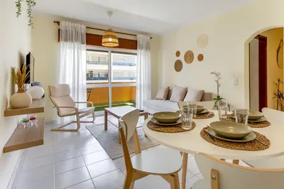 a dining room and living room with a table and chairs at 1BR Infante Flat in Quarteira by LovelyStay in Quarteira