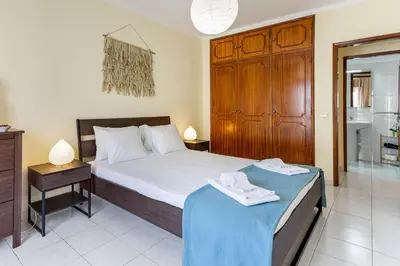 a bedroom with a large bed and a bathroom at 1BR Infante Flat in Quarteira by LovelyStay in Quarteira