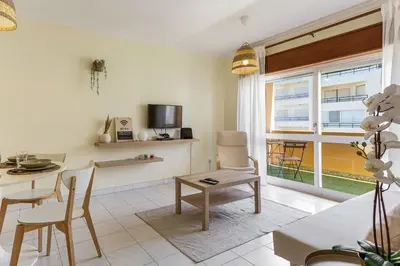 a living room with a table and chairs and a kitchen at 1BR Infante Flat in Quarteira by LovelyStay in Quarteira