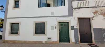 a white building with green doors and windows at Casa da Travessa - casa de férias no coração de Faro in Faro