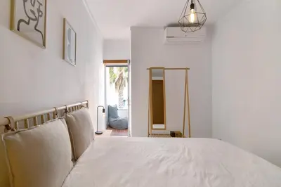 a bedroom with a bed with white sheets and a window at Ae Flat Falesia in Albufeira