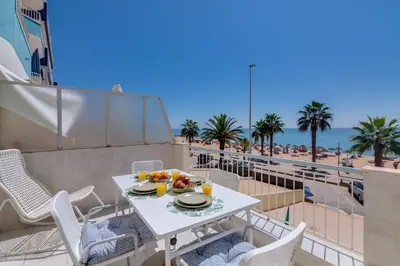a table and chairs on a balcony with a view of the beach at AL - Oceano T2 Frente Mar Quarteira in Quarteira