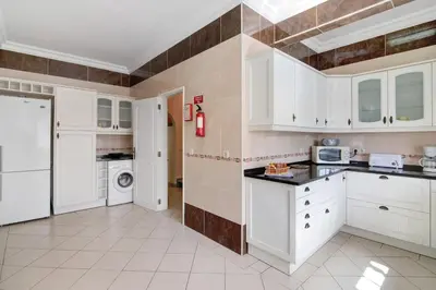 a kitchen with white cabinets and a tile wall at Villa Paraíso in Olhos de Água