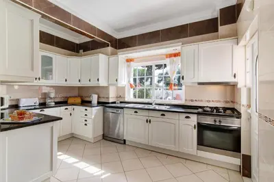 a white kitchen with white cabinets and a window at Villa Paraíso in Olhos de Água