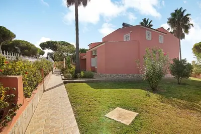 a pink house with a palm tree in a yard at Villa Paraíso in Olhos de Água