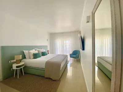 a bedroom with a large bed and a mirror at Vilamoura Avelãs Ocean View Apartment in Vilamoura