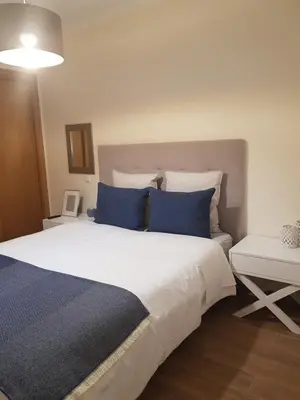 a bedroom with a large bed with blue pillows at MARINA DE ALBUFEIRA, Best Apartment in Albufeira
