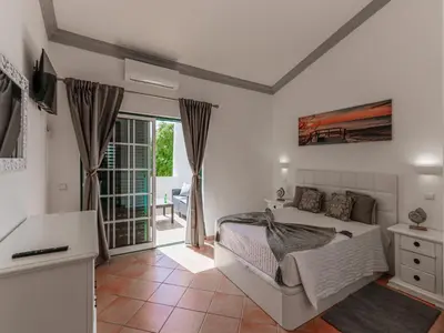 a white bedroom with a bed and a balcony at Cozy Townhouse Vila Rafaella2 near São Rafael Beach Albufeira in Albufeira