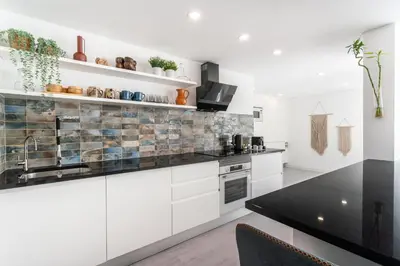 a kitchen with white cabinets and a black counter top at Privilege Deluxe Apartment Casa Mãe, Faro in Faro