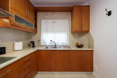 a kitchen with wooden cabinets and stainless steel appliances at Love Nest Algarve Edition vilamoura in Vilamoura