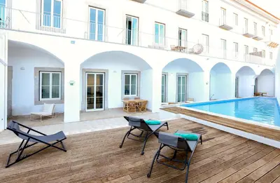a courtyard with a pool and chairs and a building at Beach Waves Apartment in Faro