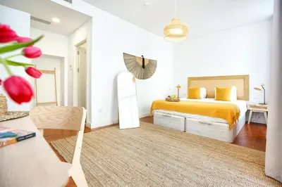 a white bedroom with a bed and a mirror at Beach Waves Apartment in Faro