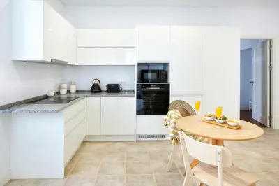 a kitchen with white cabinets and a wooden table at Coast Guard Apartment in Faro