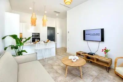 a kitchen with white cabinets and a living room at Hot Breeze Apartment in Faro