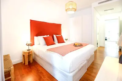 a bedroom with a large white bed with red pillows at Faro Away From Home Apartment in Faro