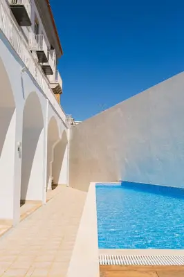 a house with a swimming pool and a white wall at Faro Away From Home Apartment in Faro