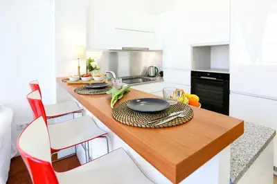 a kitchen with a wooden table and white cabinets at Jump Into the Lull Apartment in Faro