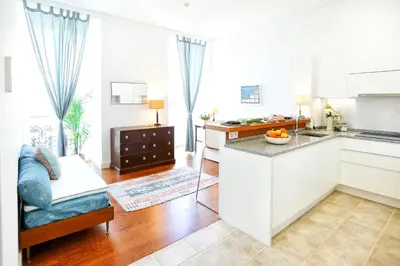 a kitchen and living room with white cabinets at Jump Into the Lull Apartment in Faro