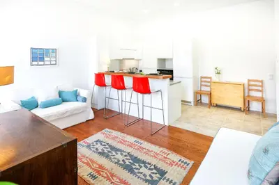 a living room with a couch and a kitchen at Jump Into the Lull Apartment in Faro