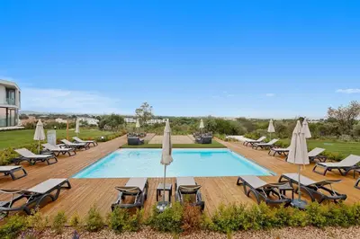 a swimming pool with lounge chairs and umbrellas at Balaia Senses in Albufeira