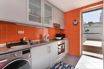 a kitchen with orange walls and a sink and a dishwasher at Lemon Hostel Faro in Faro