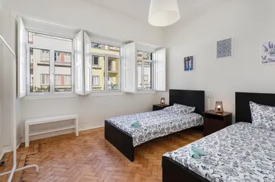 a bedroom with two beds and two windows at Lemon Hostel Faro in Faro
