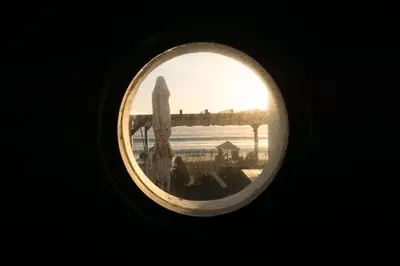 a view of the sunset through a round window at Wax Suite By the sea in Faro