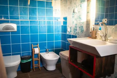 a blue tiled bathroom with a sink and a toilet at Wax Suite By the sea in Faro