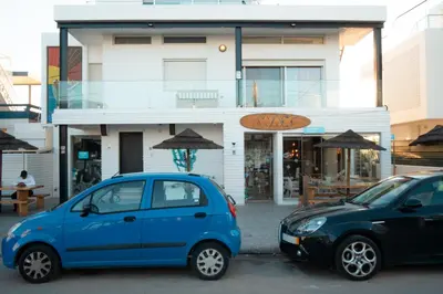 two cars parked in a parking lot in front of a building at Wax Suite By the sea in Faro