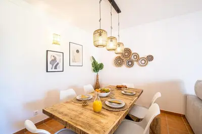 a dining room with a wooden table and white chairs at Villa Jasmin - Galé Bay in Albufeira