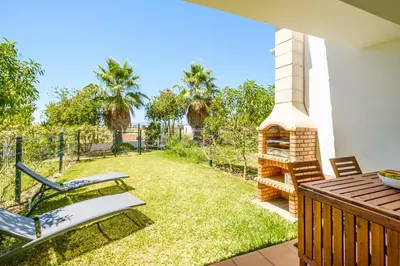 a backyard with a grill and chairs on a patio at Villa Jasmin - Galé Bay in Albufeira
