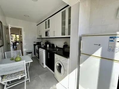 a kitchen with a washer and dryer and a refrigerator at Quarteira Stylish 1 by Homing in Quarteira