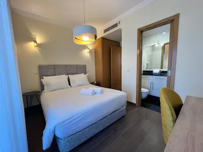 a bedroom with a large white bed and a bathroom at Light House Luxury Villa in Albufeira