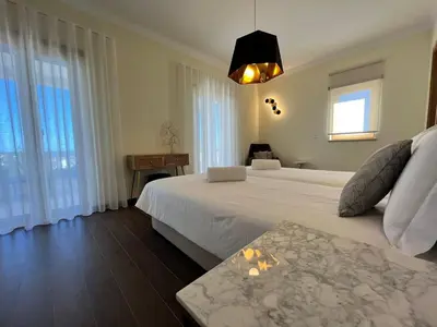 a bedroom with a large white bed and windows at Light House Luxury Villa in Albufeira