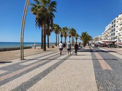 a group of people walking down a sidewalk near the beach at T2-MAMAMIA II Frente Mar in Quarteira
