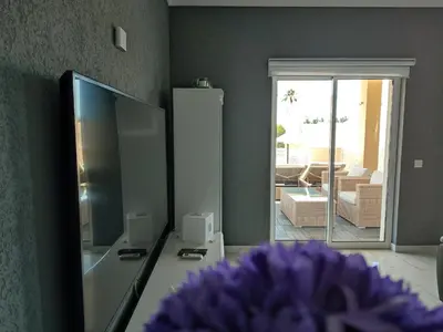 a living room with a mirror and a table with a purple flower at Casa das Oliveiras o seu refugio no Algarve in Quarteira