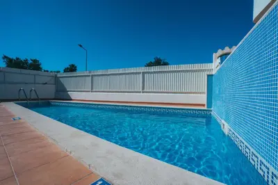 a swimming pool next to a building with a fence at Torre da Aldeia by Umbral in Albufeira