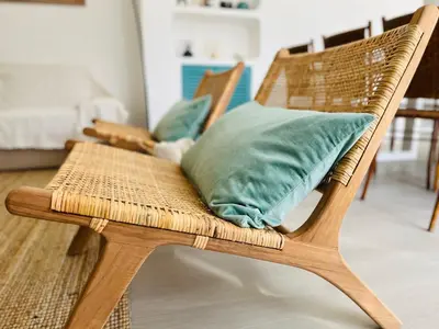 a wicker chair with a green pillow in a room at Amazing - VillaAnas Balaia in Albufeira